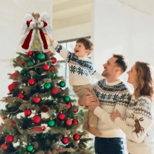 Heartwarming Christmas moment: father helps boy put angel tree topper while mother looks on smiling