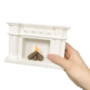 A hand is holding the dollhouse fireplace set